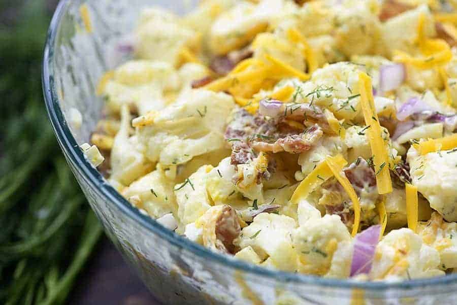 Glass bowl of cauliflower salad stirred up.