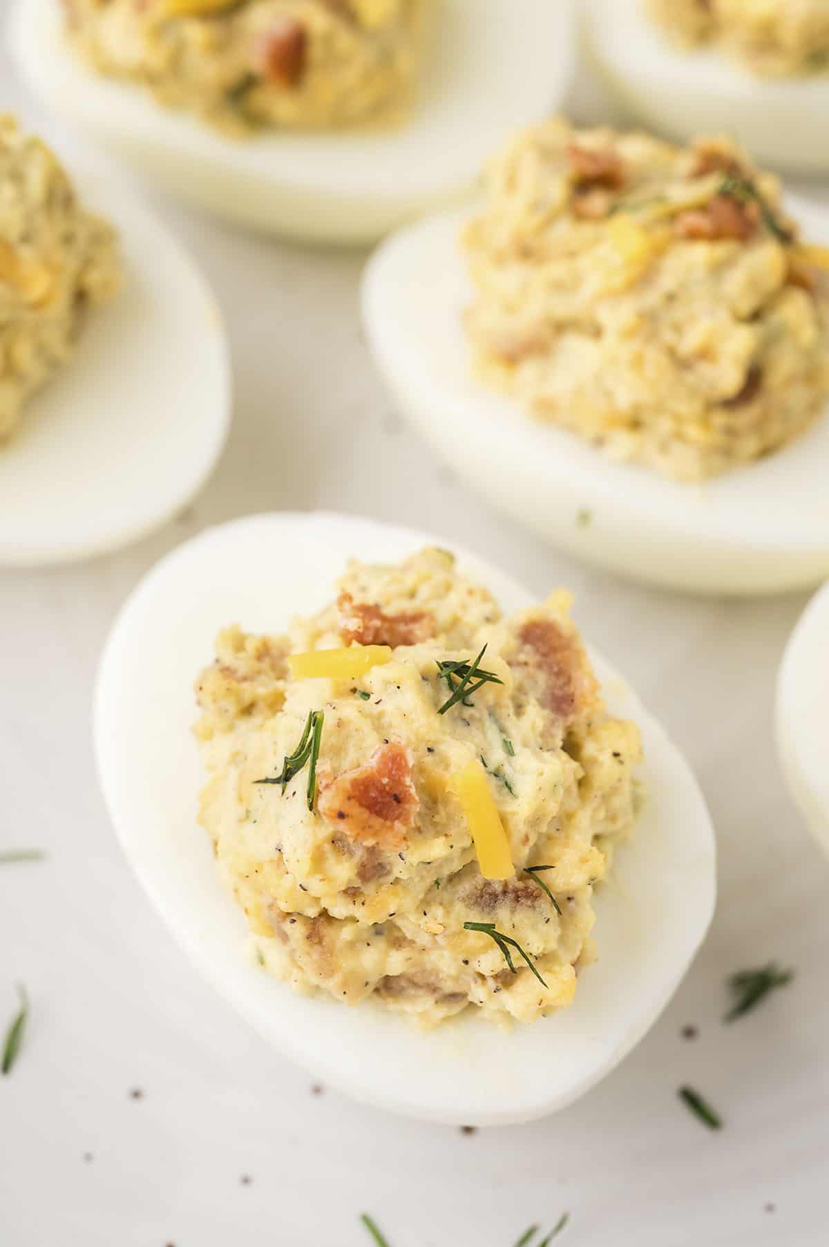 keto deviled eggs on wooden cutting board with bacon