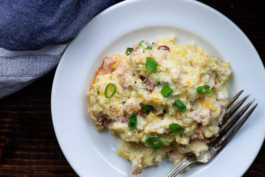 Cooked cauliflower casserole on small white plate with fork.