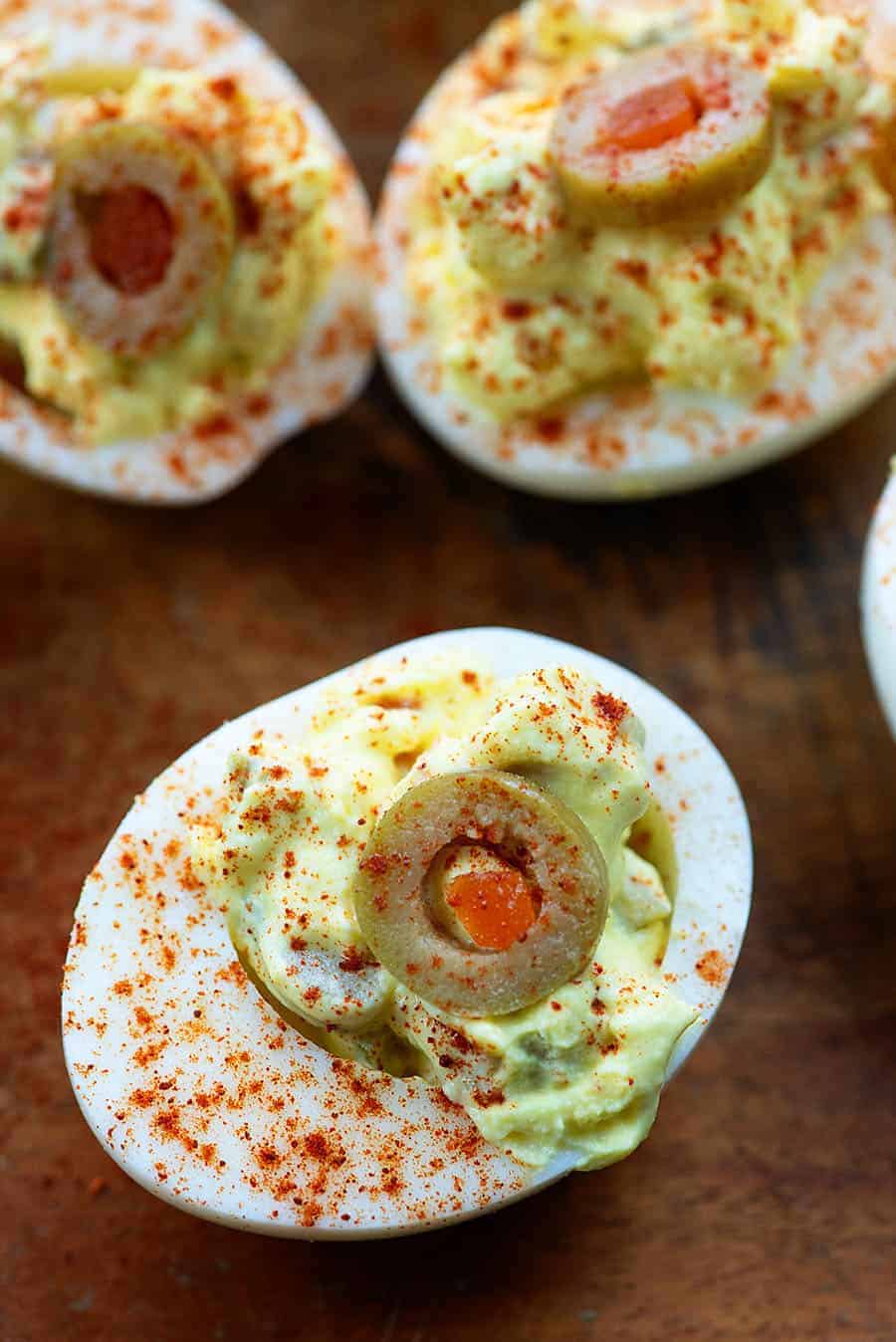 deviled eggs made with green olives on wood cutting board