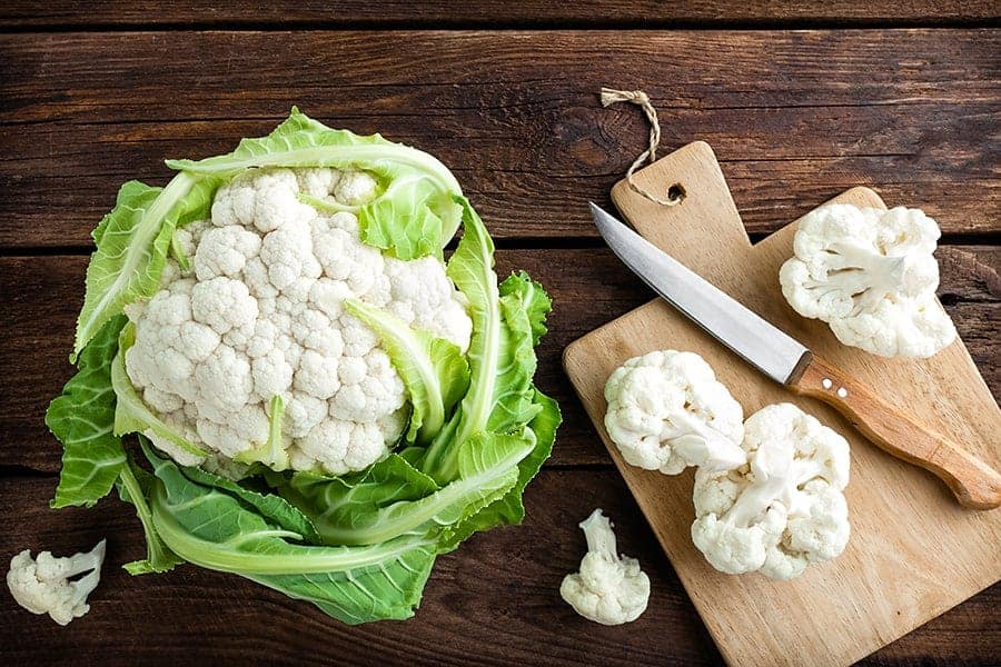 cutting cauliflower wooden background