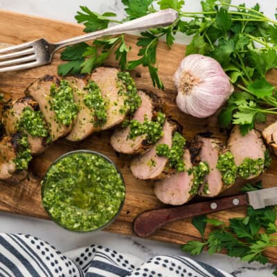 POrk tenderloin with chimichurri on cutting board.