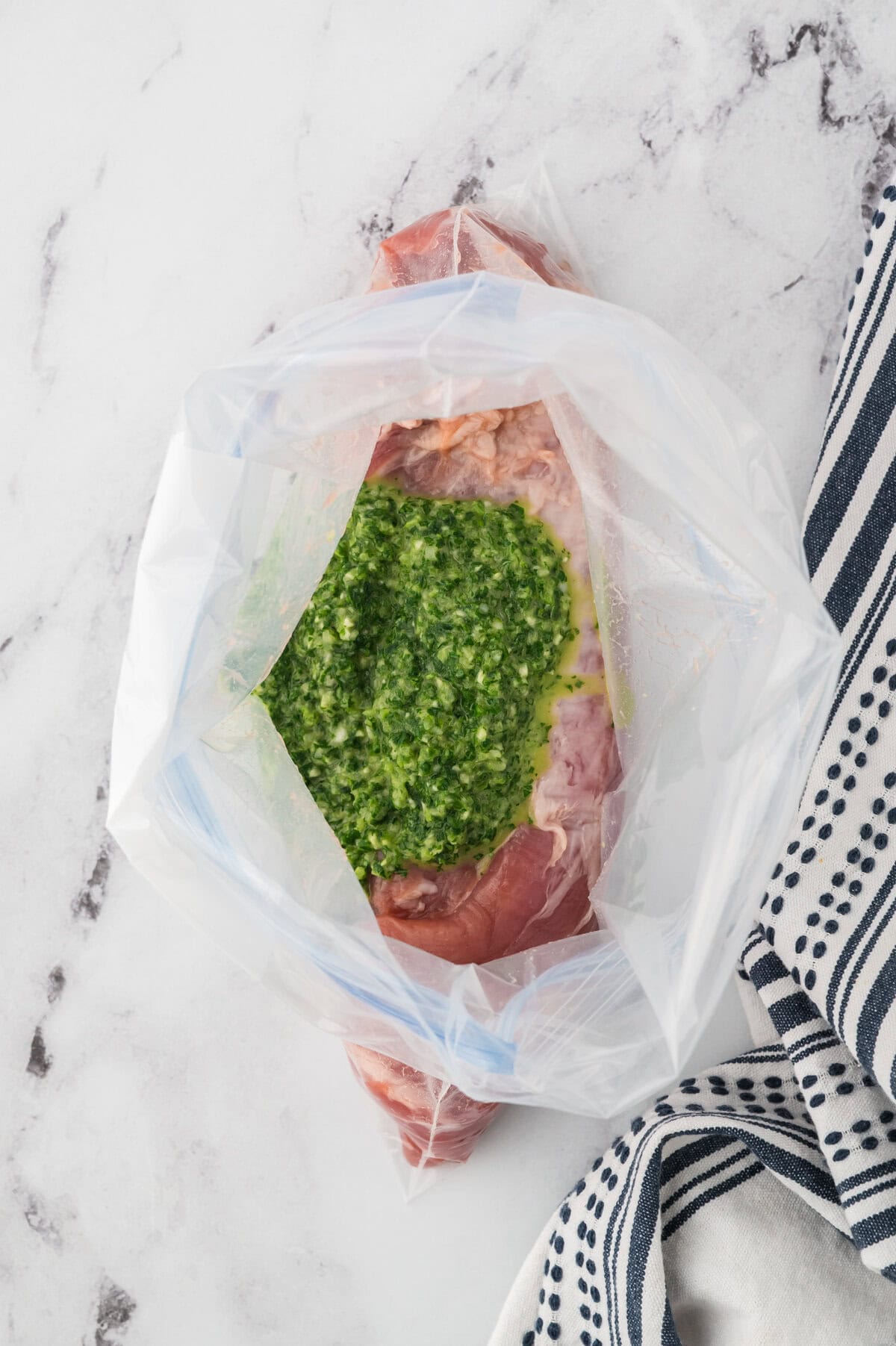 Pork tenderloin in zip top bag with chimichurri.
