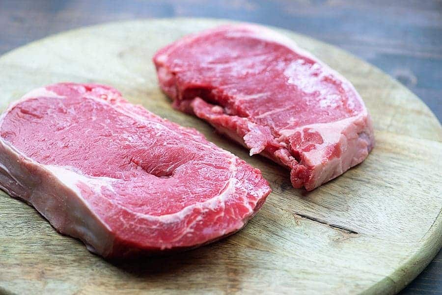Raw steak on cutting board.