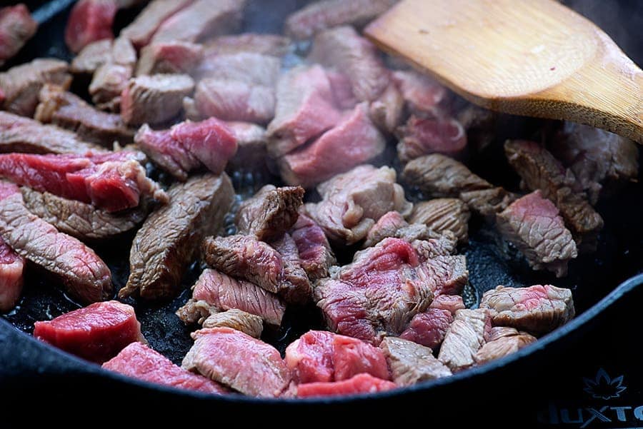 Beef cooking in cast iron skillet.