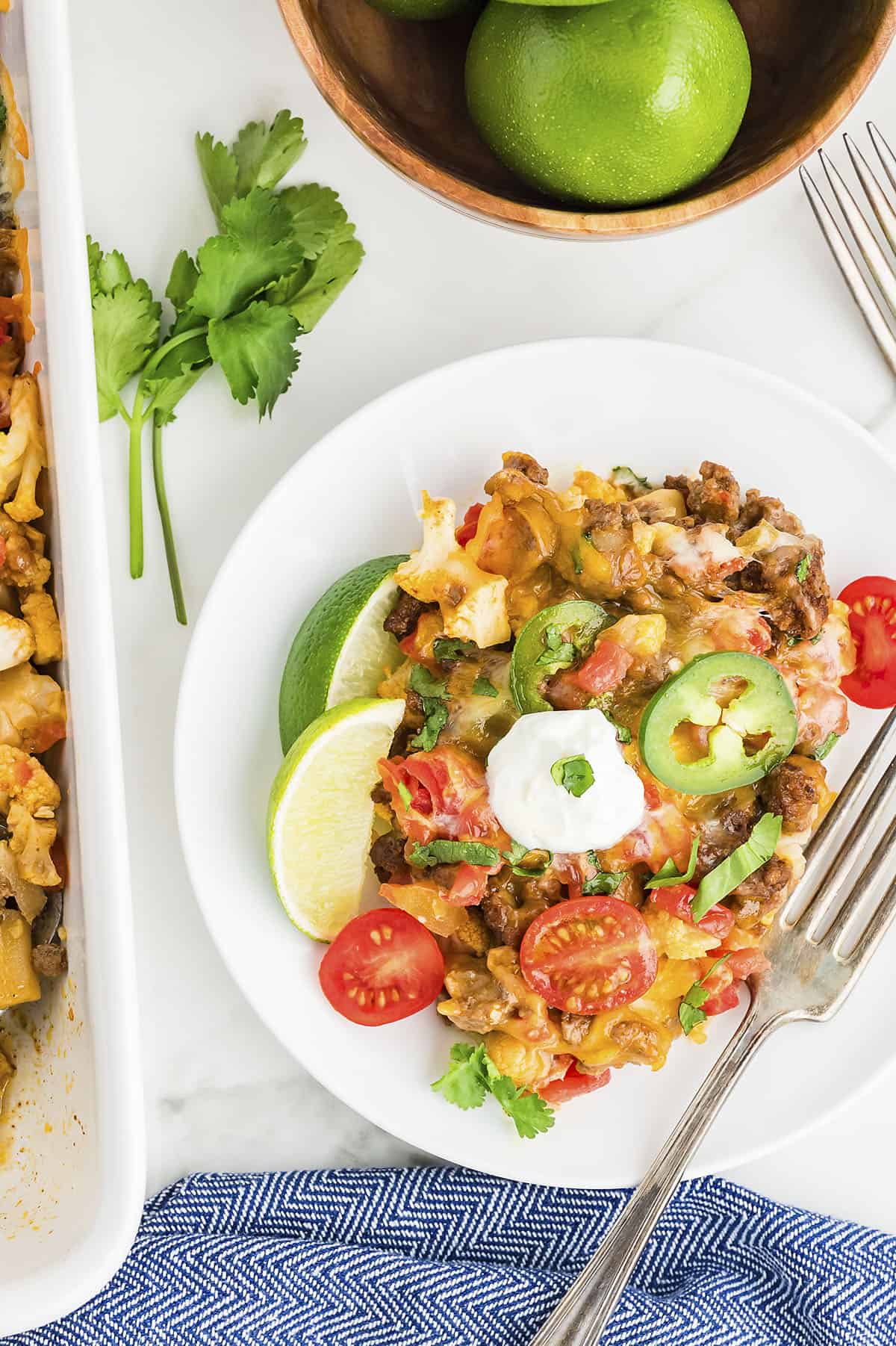 low carb taco casserole on white plate with pan near it.