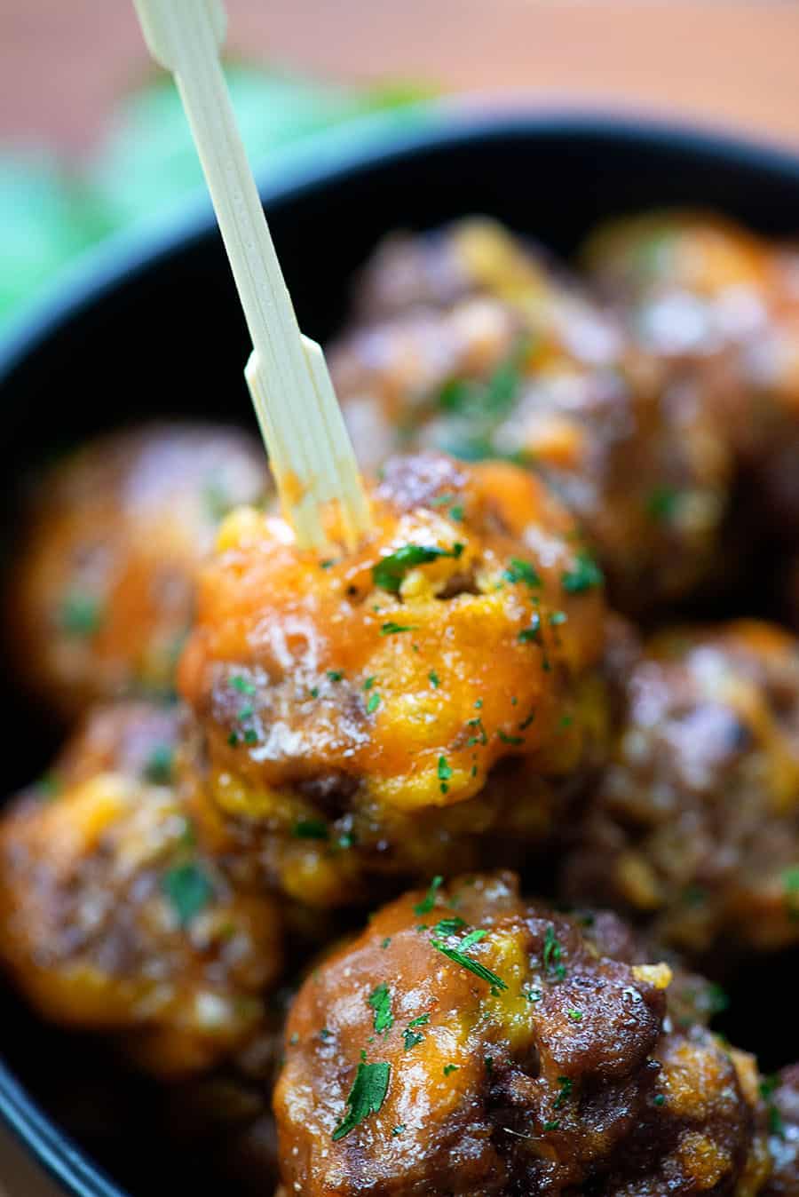 bbq meatballs in a black bowl with a toothpick in one of them