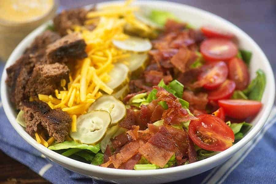 cheeseburger salad in white bowl with fresh ingredients
