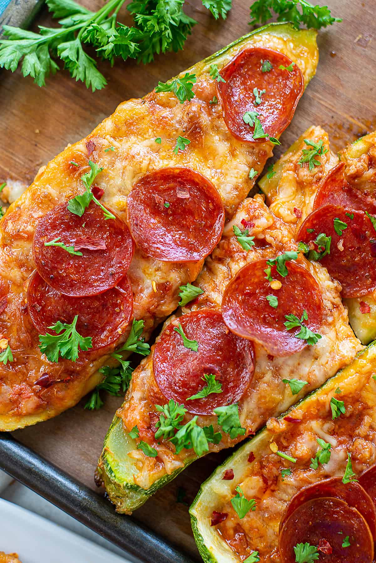 overhead view of zucchini pizza boats on wooden tray.