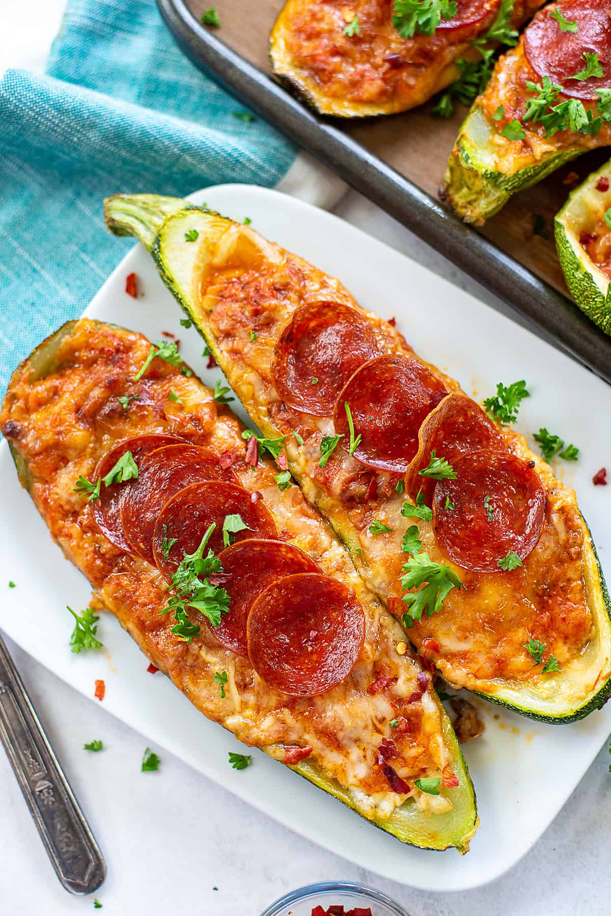 baked zucchini pizza boats on white plate.