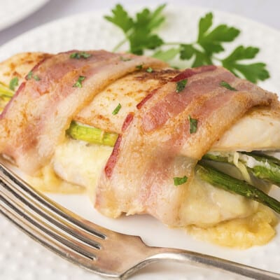Asparagus stuffed chicken on white plate.