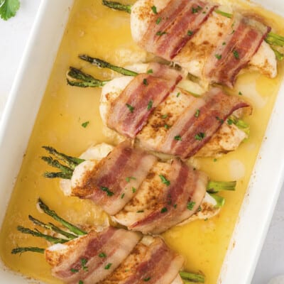 Baked chicken breasts stuffed with asparagus in white pan.