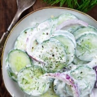A close up of a bowl of food, with Cucumber and Salad