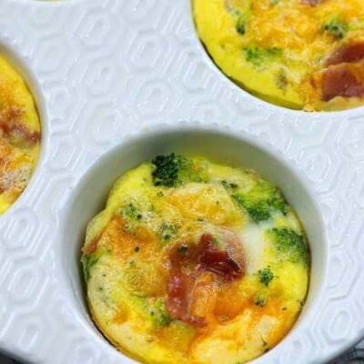 white Muffin Tin containing a few cookedFrittata with bacon, cheddar, and broccoli