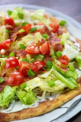 pizza crust with cheese, lettuce and tomatoes on top