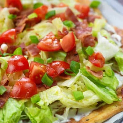 pizza crust with cheese, lettuce and tomatoes on top