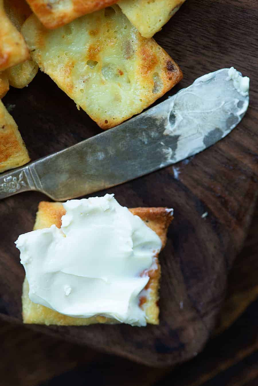 spreading cream cheese on a ranch cracker