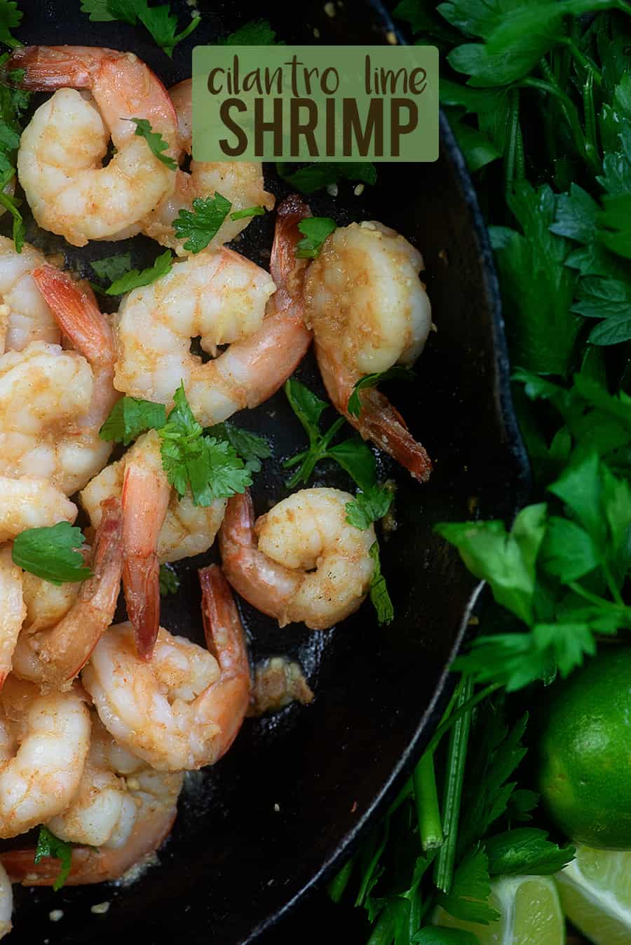 shrimp in a skillet surrounded by cilantro and limes