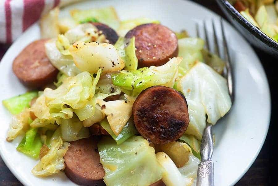 Smoked sausage and cabbage on a white plate.