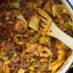 cabbage and sausage in a dutch oven with a wooden spoon stirring it
