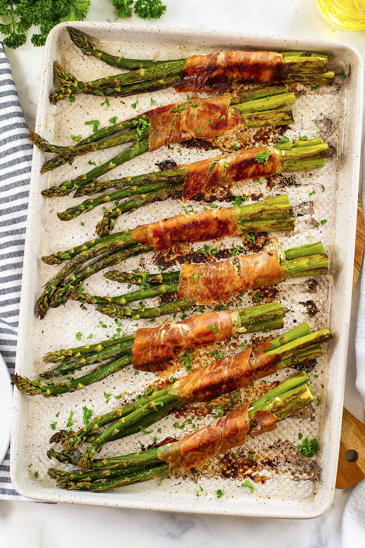 Prosciutto wrapped asparagus on baking sheet.