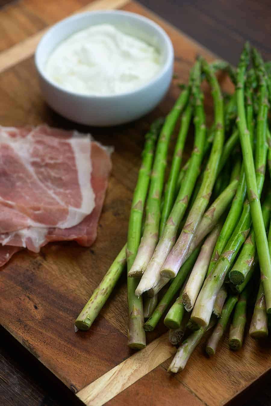 ingredients for prosciutto wrapped asparagus on wooden cutting board