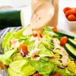Thousand island dressing being drizzled over salad.
