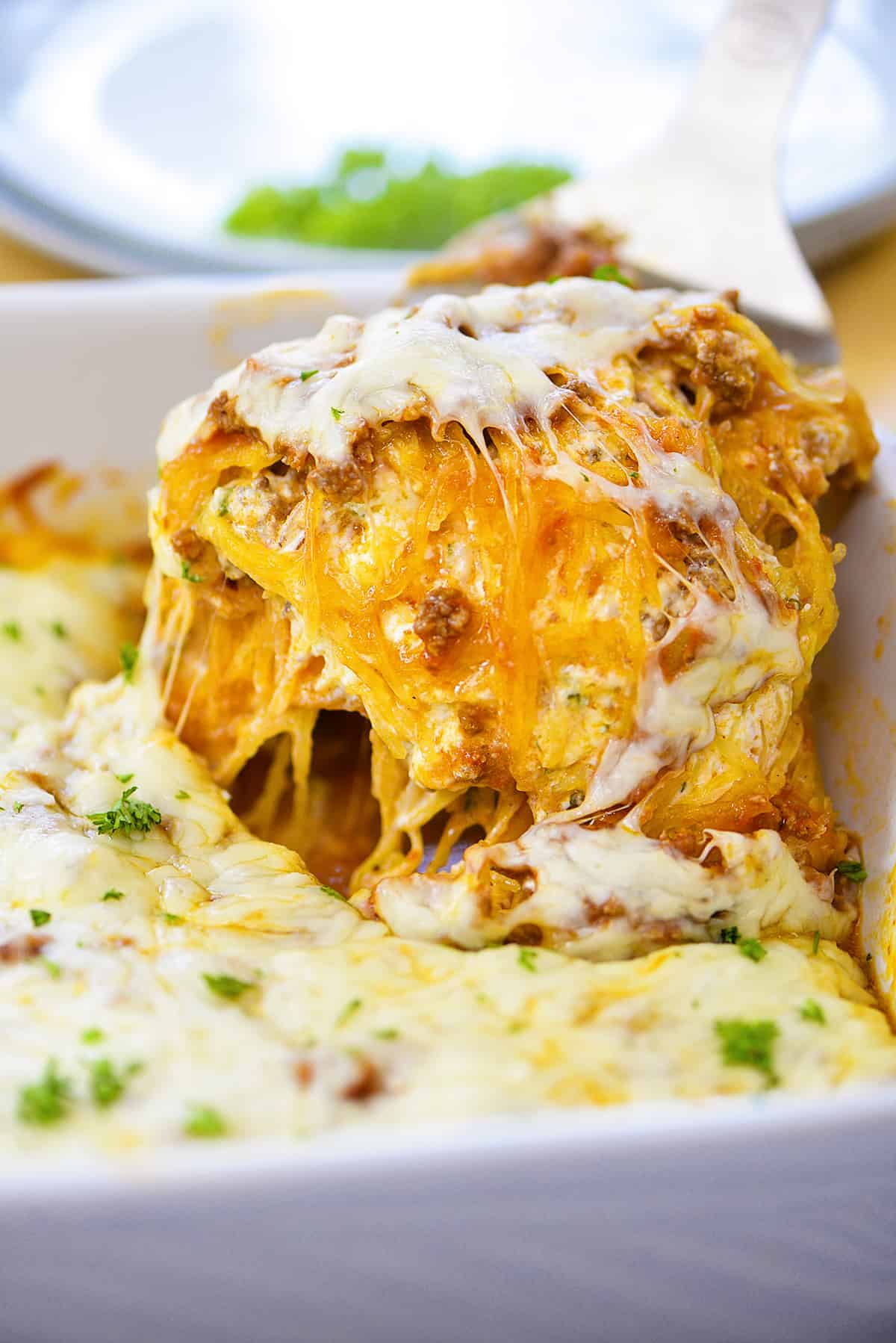 Scoop of spaghetti squash casserole being taken out of casserole dish.