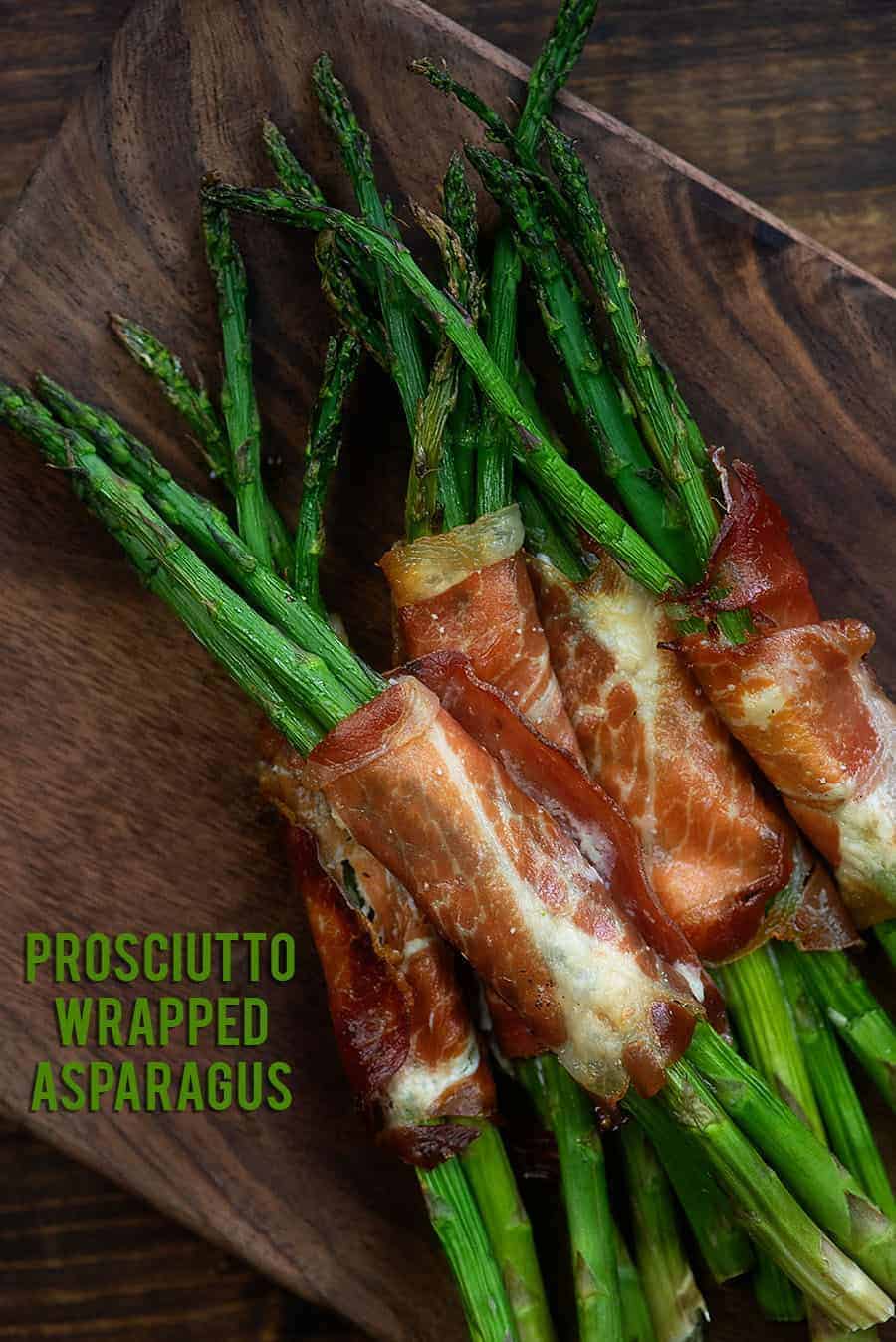 Prosciutto wrapped asparagus  on a wooden plate