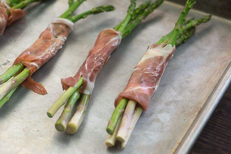 prosciutto wrapped asparagus on baking sheet