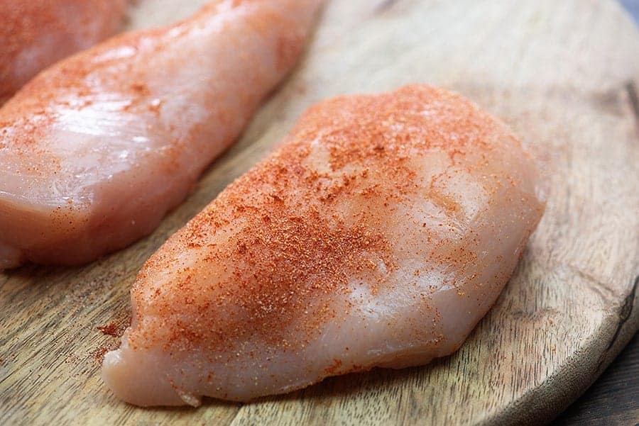 condimento per petti di pollo su tagliere di legno