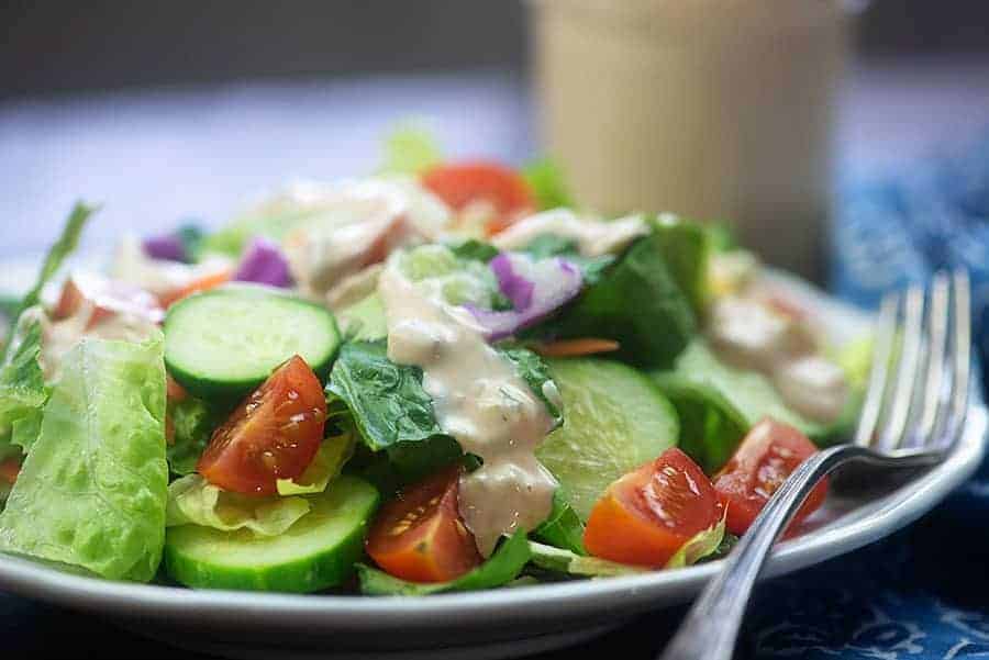 white plate of salad with thousand island dressing