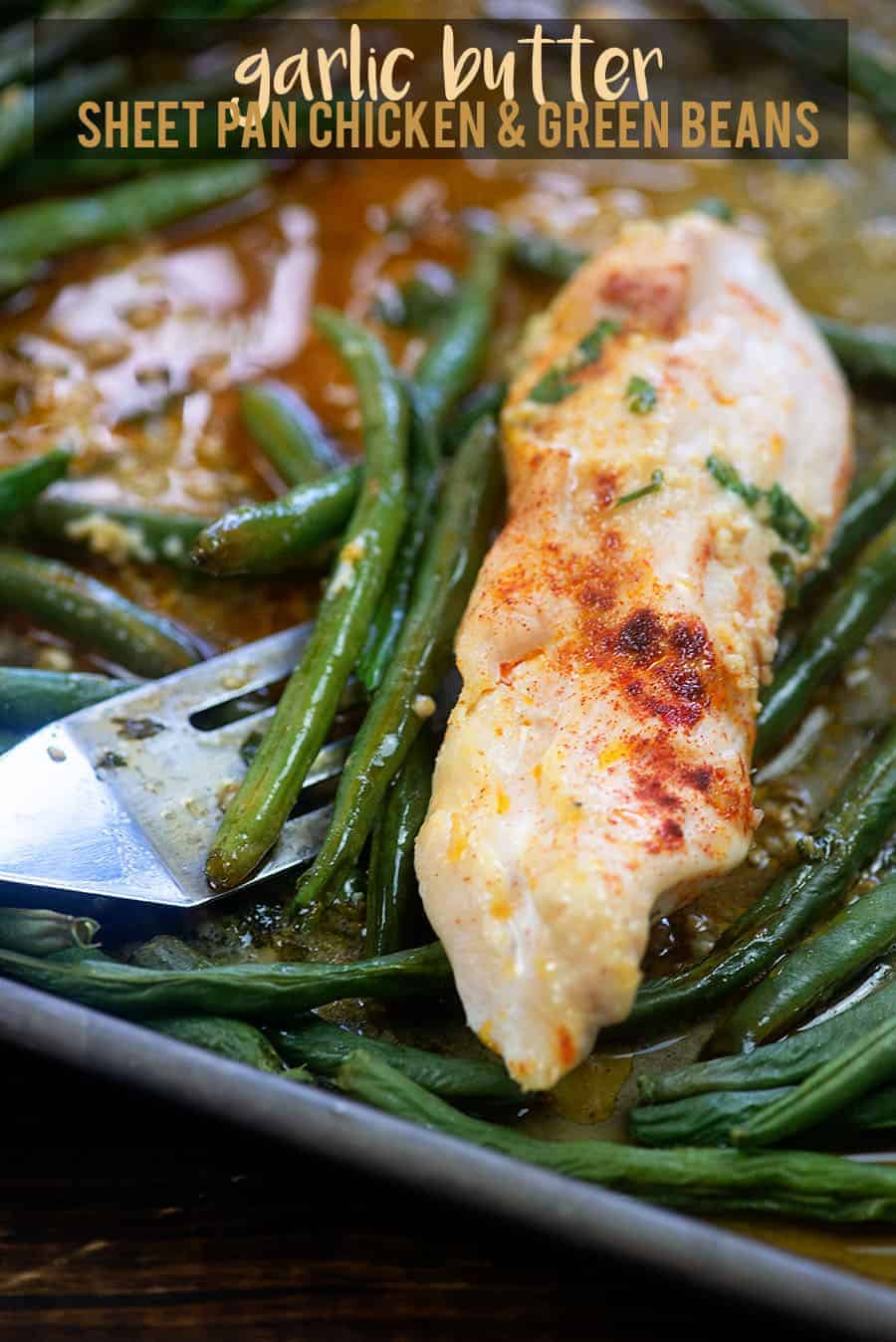 garlic butter chicken and green beans getting scooped off a baking sheet