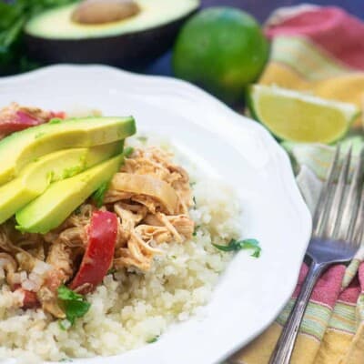 diced cauliflower, chicken, and avocado slices on a small white plate