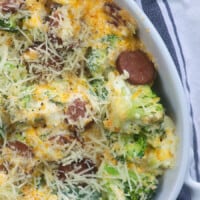 White oval baking pan with sliced sausages and cheese