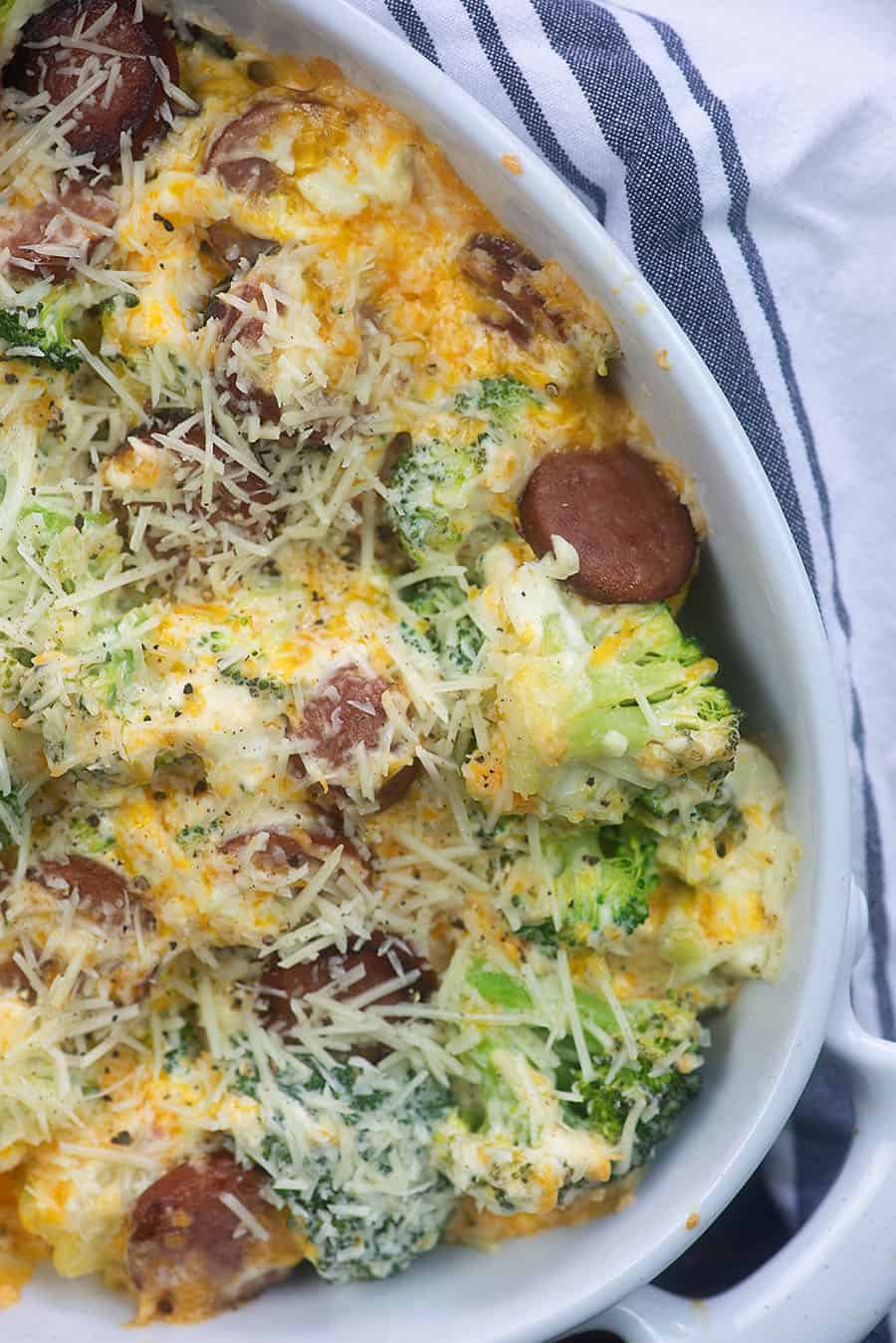 White oval baking pan with sliced sausages and cheese