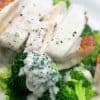 A close up of a plate of food with broccoli, with Alfredo sauce and Chicken