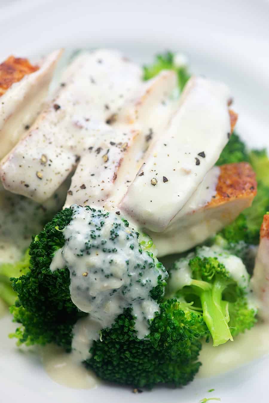 A close up of a plate of food with broccoli, with Alfredo sauce and Chicken