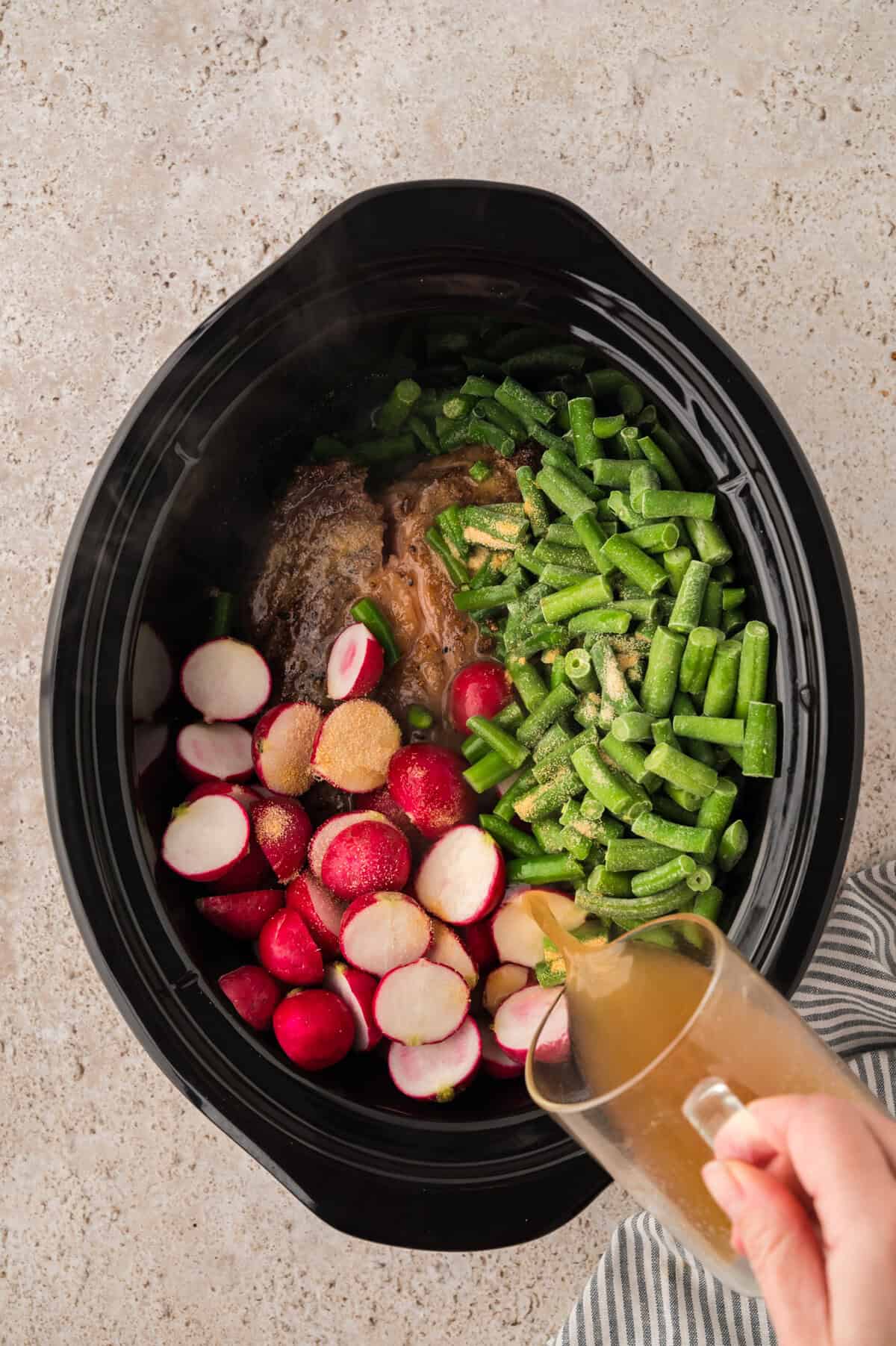 Chuck roast, radishes, and green beans in slow cooker with beef broth.