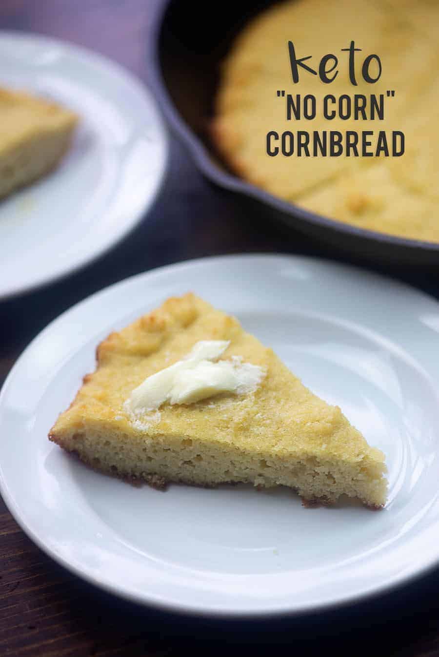 A triangle piece of cornbread topped with butter on a white plate.