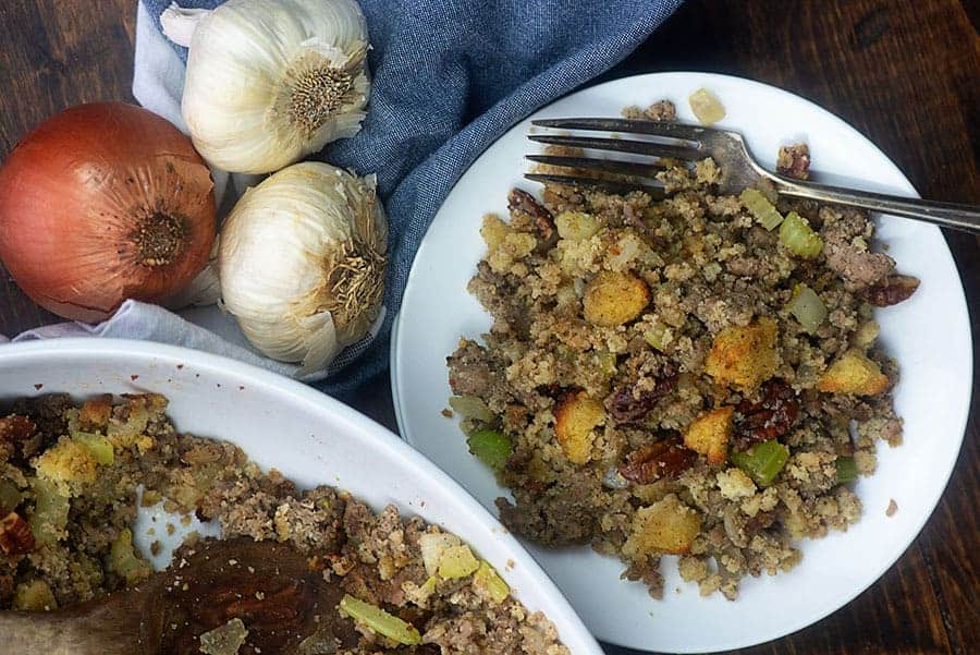 white plate of sausage stuffing next to  an oniion and garlic