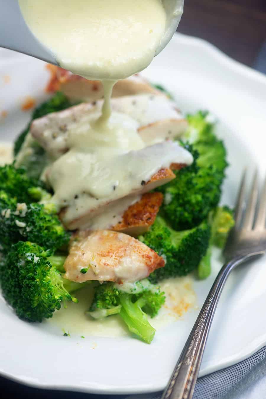 drizzling low carb Alfredo sauce over chicken and broccoli