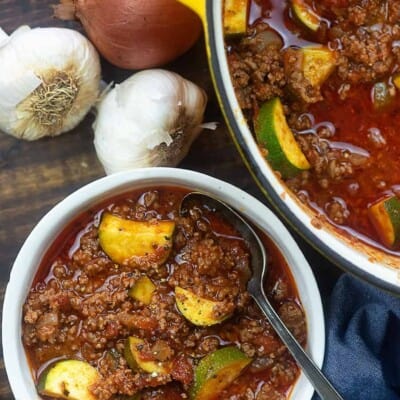 bowl of goulash next to whole garlic and onions