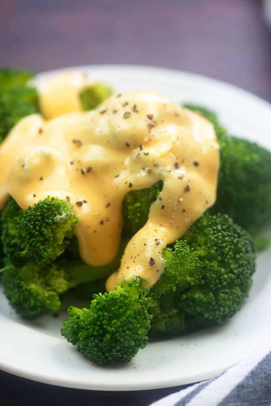 A plate of broccoli topped with cheese sauce