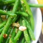 green beans with butter and diced almonds in a white bowl