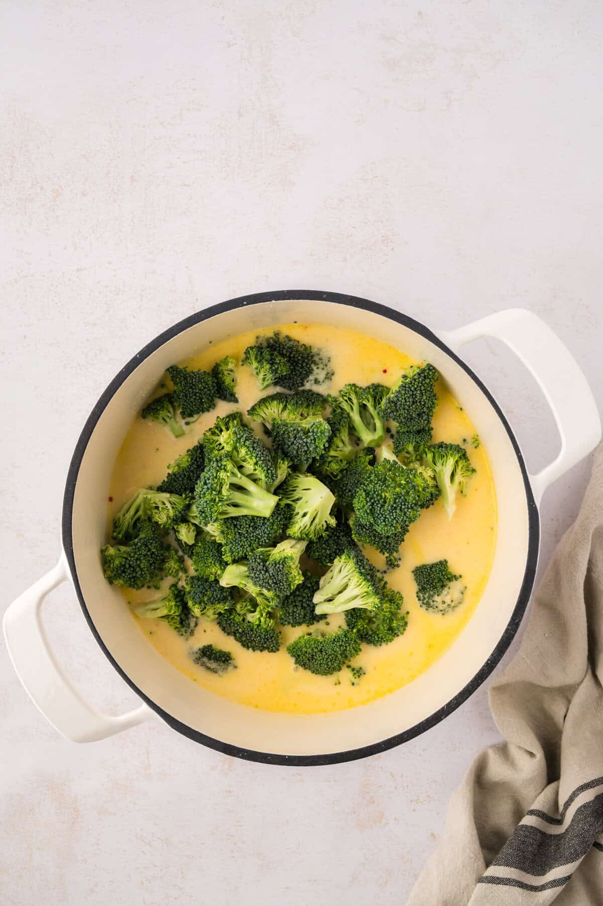 Broccoli florets in pot of soup.