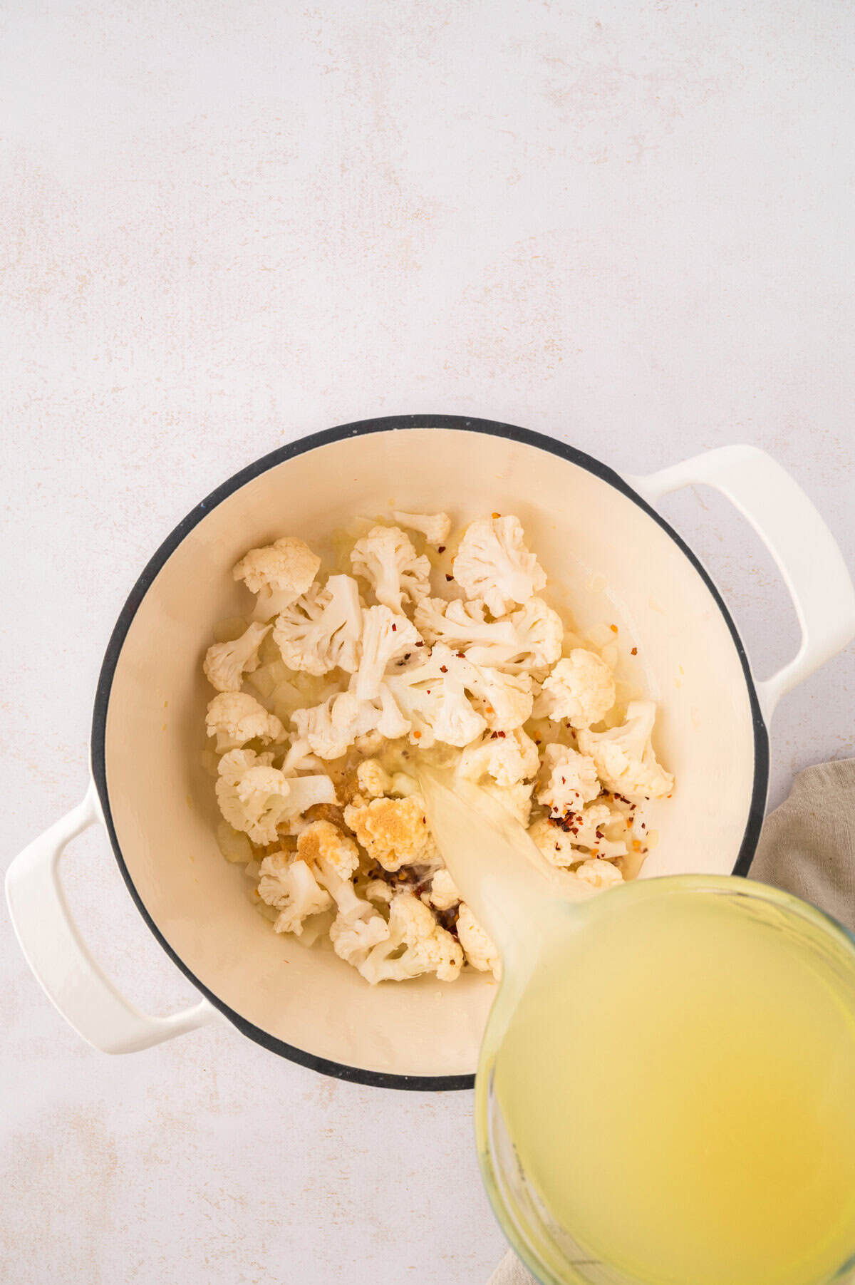 Cauliflower and broth in soup pot.