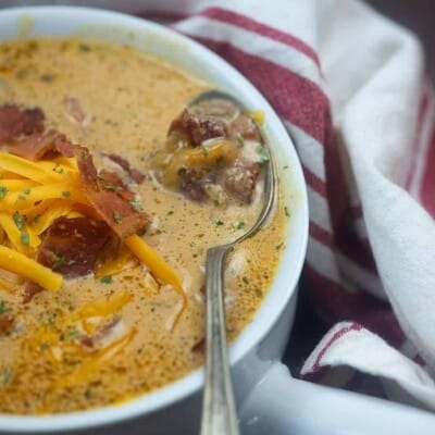 A bowl of food on a plate, with Soup and Bacon