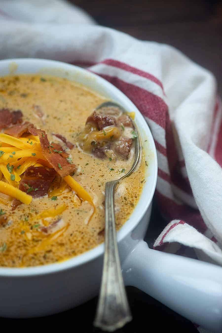 white bowl full of bacon cheeseburger soup with a white dish towel