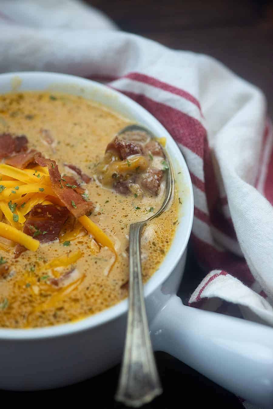 A bowl of food on a plate, with Soup and Bacon